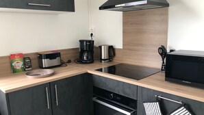 A modern kitchen with a black stove, a coffee maker, a kettle, and a microwave. - 75 m2 # logia # parking # BESTOFBLO 4 # INSEAD (Fontainebleau)
