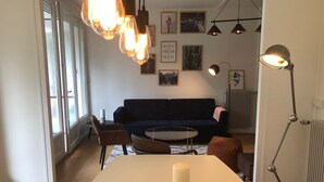 A modern living room with a dark blue sofa, a round coffee table, and a white dining table with two candles. - 75 m2 # logia # parking # BESTOFBLO 4 # INSEAD (Fontainebleau)