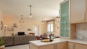 Een moderne keuken met lichte houten kastjes, een centraal eiland en hangende lampen.