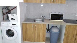 A compact kitchen with a washing machine, a microwave, and a sink. - Pretty Apartment 15 min walk from the Promenade des Anglais (Nice)