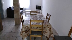 A dining area with a table set for four, surrounded by wooden chairs. A television is mounted on the wall to the right. - Pretty Apartment 15 min walk from the Promenade des Anglais (Nice)