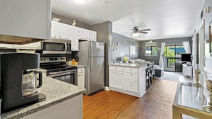 A modern kitchen with white cabinets, stainless steel appliances, and a wooden floor. - Port Royal Sound 2BR Villa Balcony, Pools & Beach Access (Hilton Head Island)