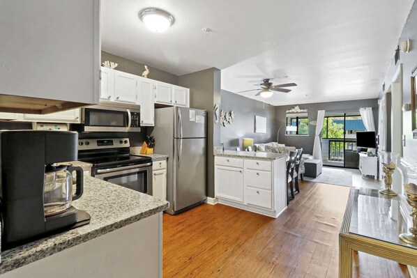 A modern kitchen with stainless steel appliances, a coffee maker, and a dining area with a view.