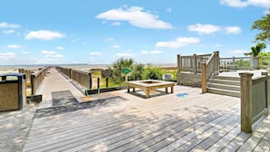 A wooden deck with a view of the beach, a picnic table, and a sign indicating a nature trail. - Port Royal Sound 2BR Villa Balcony, Pools & Beach Access (Hilton Head Island)