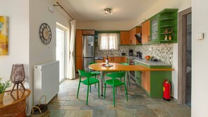 Een keuken met groene kastjes, een houten tafel en groene stoelen.