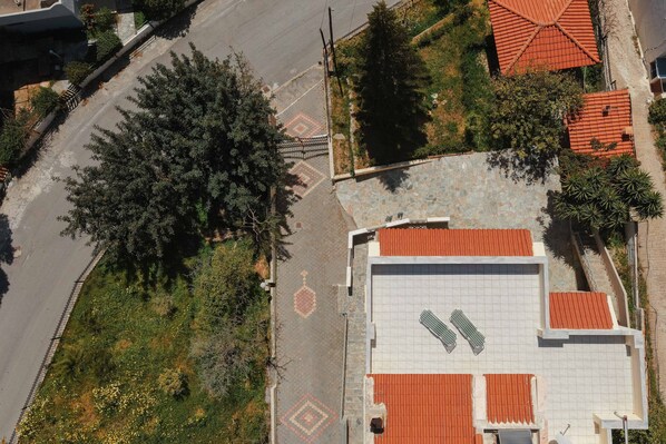 Vista aerea di un edificio con tetto in tegole, circondato da alberi e un'area pavimentata.