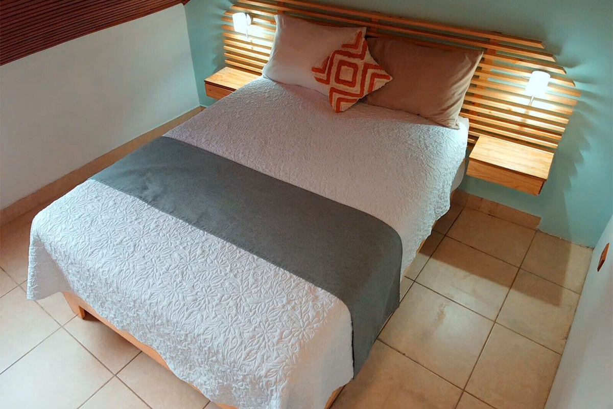 A bed with a patterned bedspread, a pillow with a geometric design, and wooden headboards with built-in lighting.
