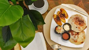 Un plato con comida y bebidas sobre una mesa con una planta y una cesta.