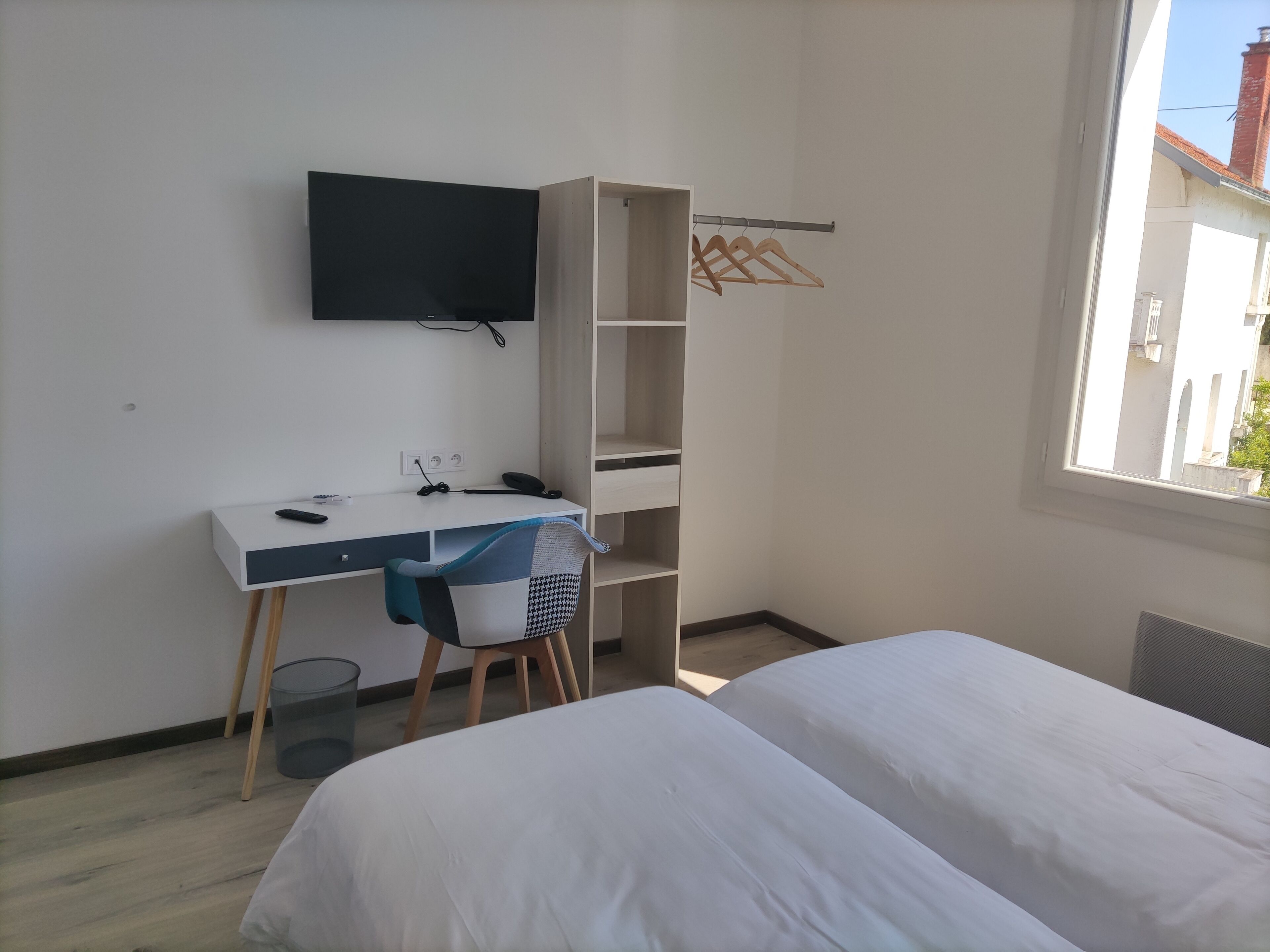 A bedroom with a bed, a desk, a chair, a TV, and a wardrobe.