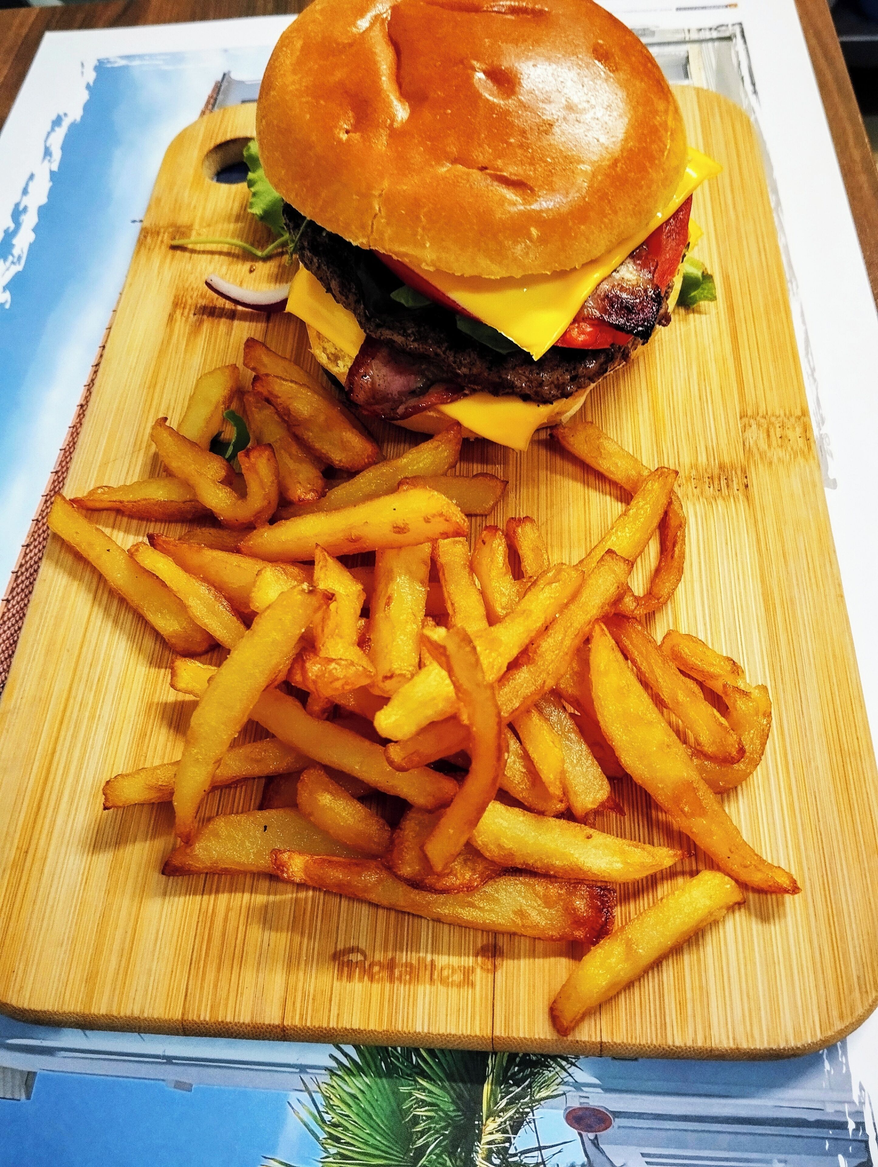 Comida que incluye una hamburguesa y papas fritas sobre una tabla de madera.