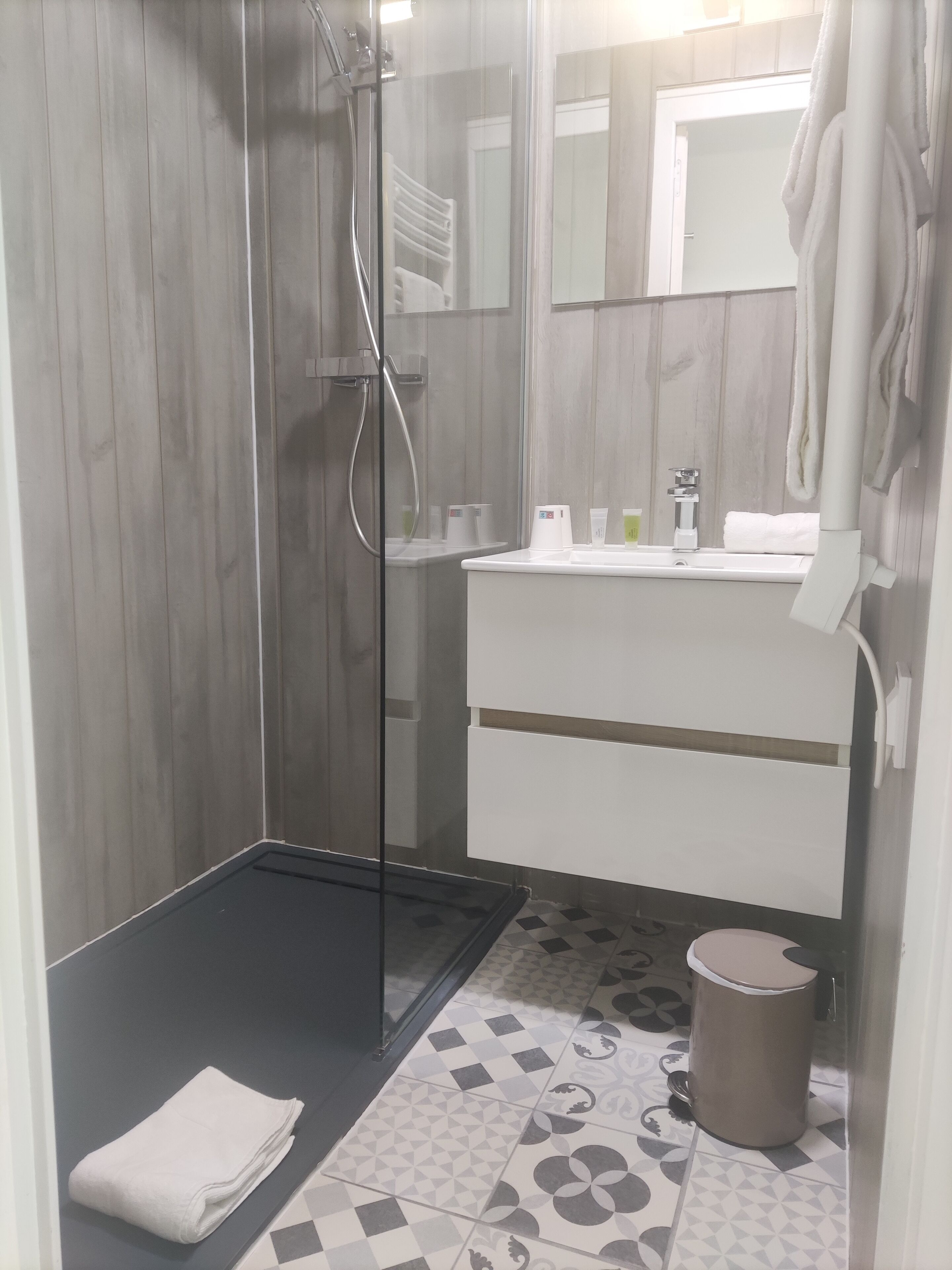 Ein modernes Badezimmer mit einer Duschkabine aus Glas, einem weißen Waschbecken und einem Spiegel darüber.