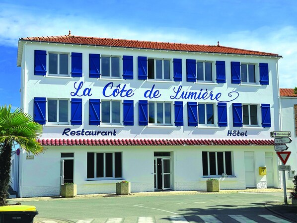 Un edificio de dos pisos con un letrero que dice "La Côte de Lumière Restaurant" y "Hotel".