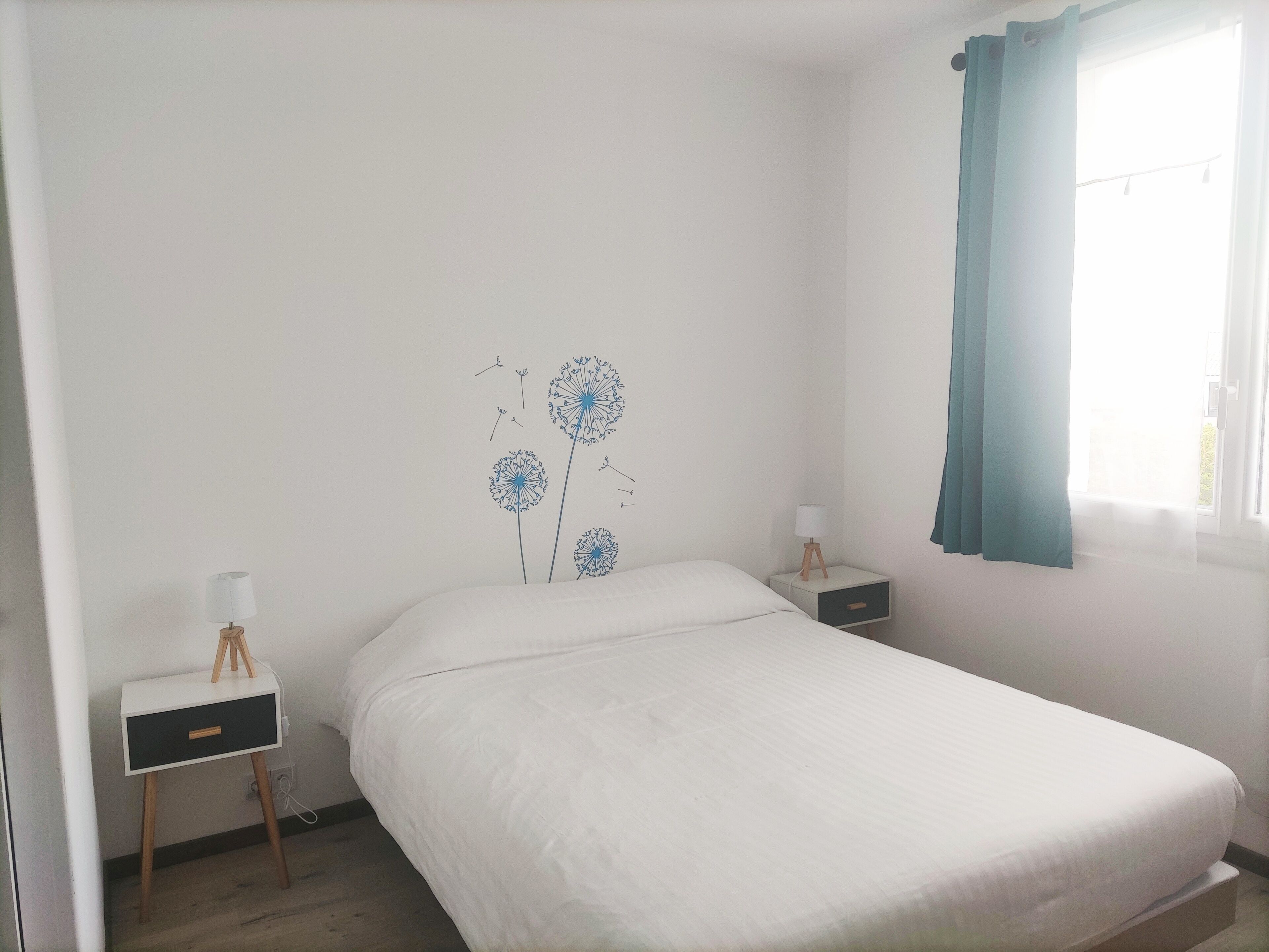 Un dormitori amb llit, una tauleta de nit, una làmpada i una decoració a la paret.