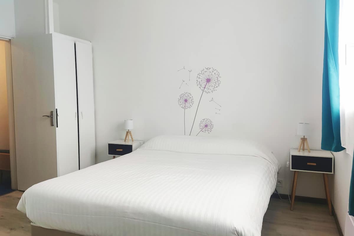 Een slaapkamer met een bed, twee nachtkastjes, een kledingkast en een decoratie aan de muur.