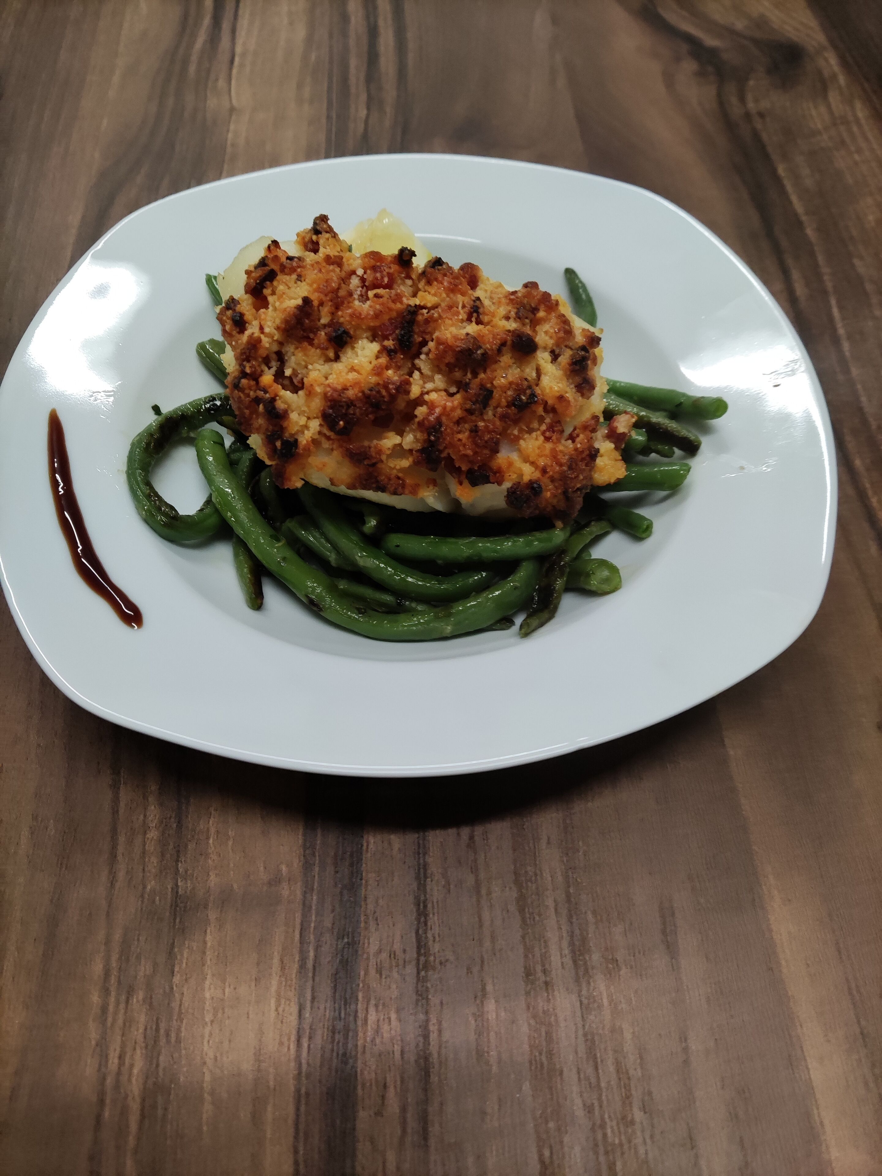 A white plate with a piece of food on a wooden table.