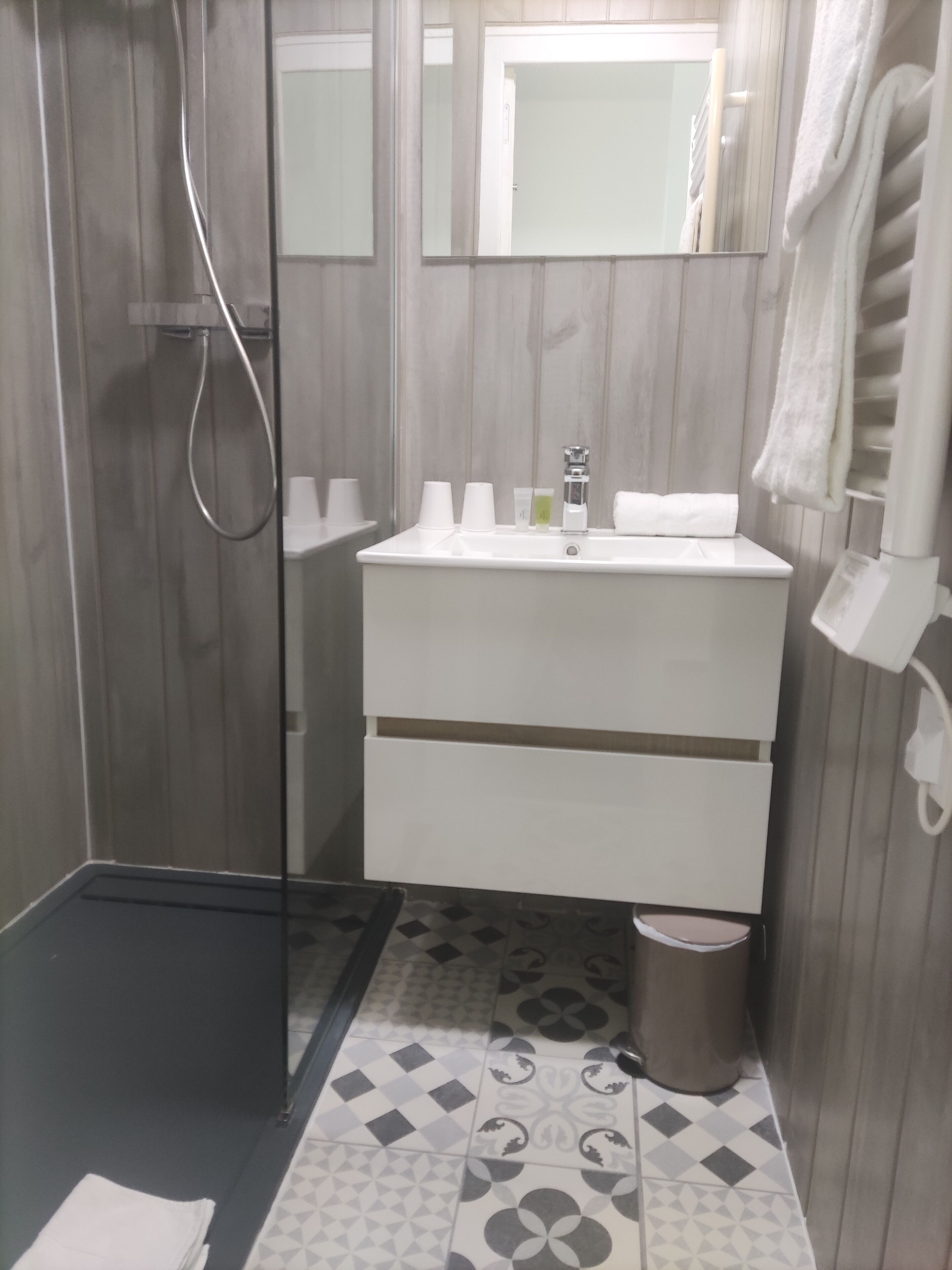A bathroom with a shower, a sink with toiletries, and a mirror.