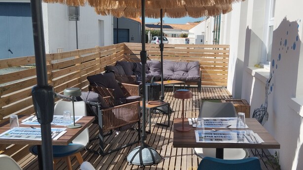 Een terras met houten meubels, een zwaan decoratie en een rieten parasol.
