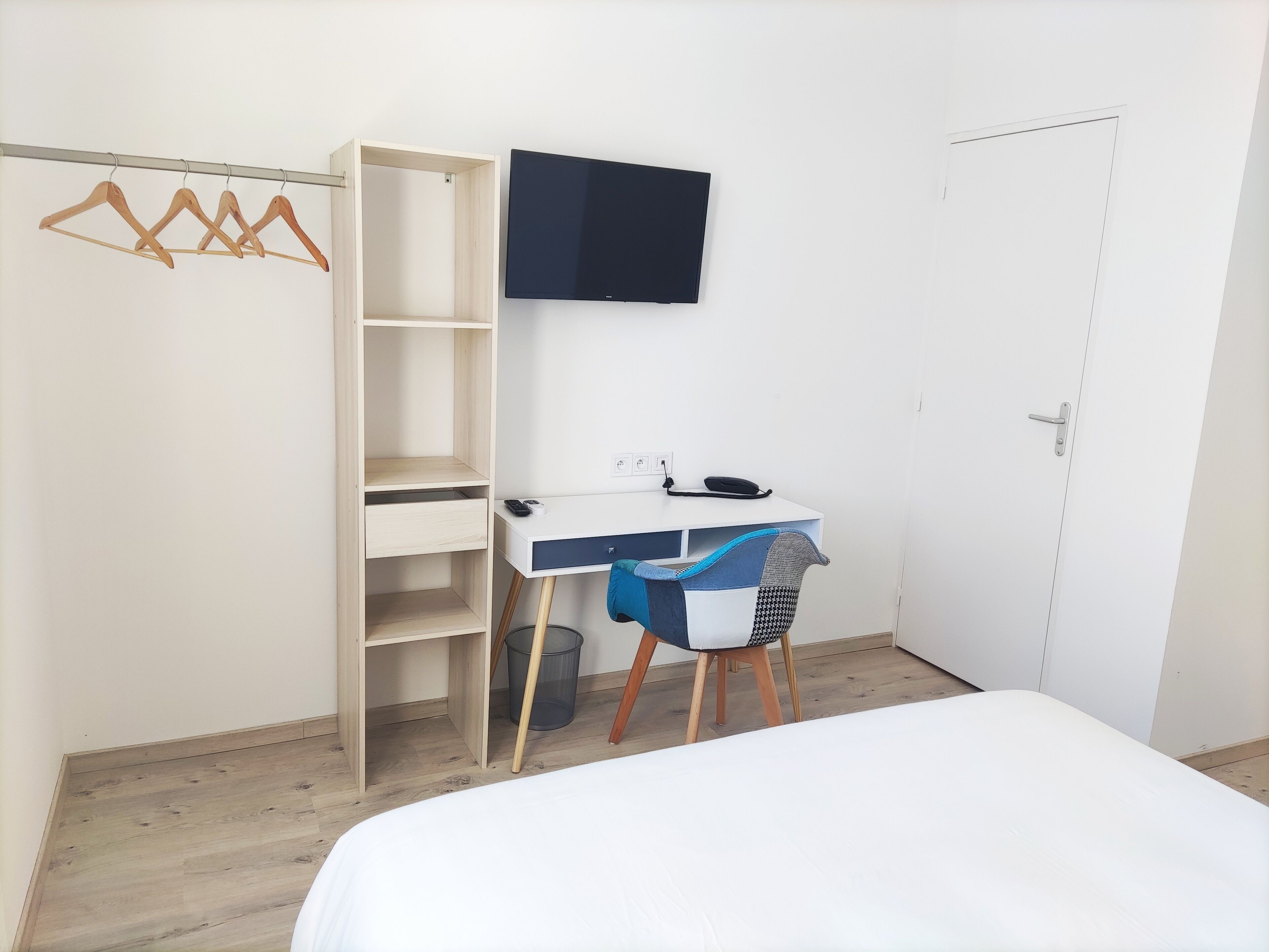 Un dormitorio con cama, escritorio con silla, armario y televisor.