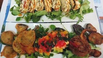 A meal with grilled chicken, vegetables, and bread on a white plate.