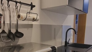 A modern kitchen with a built-in oven, a sink, and a range hood. - Lovingly furnished FeWo zum Hirschen (Herzberg am Harz)