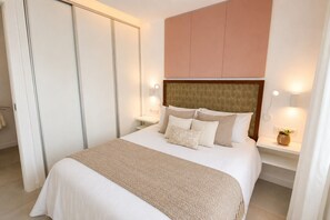 A neatly made bed with a headboard, bedside tables with lamps, and a wardrobe. - Riviera del Sol, walking distance to the beach (Mijas Costa)