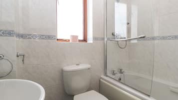 Une salle de bain comprenant des toilettes, une baignoire et un espace douche.