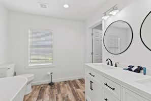 A bathroom with a toilet, bidet, and a large mirror. - Bayfront Property - Sunsets, Fishing, Wildlife Viewing (Gulf Shores)