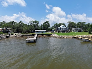 A waterfront property with a dock, a house, and a small building. - Bayfront Property - Sunsets, Fishing, Wildlife Viewing (Gulf Shores)