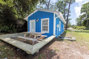 A small blue building with a wooden deck and picnic table. - Bayfront Property - Sunsets, Fishing, Wildlife Viewing (Gulf Shores)