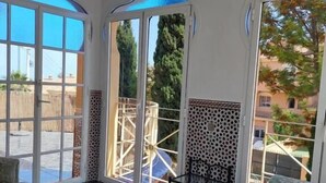 A spacious room with a large glass door leading outside, a ceiling fan, and a patterned sofa. - Villa Zafira (Benalmádena)