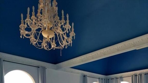 A room with a large bed, a television on a wooden cabinet, a chandelier, and two windows with curtains. - Villa Zafira (Benalmádena)