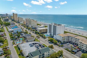 Un hôtel situé sur la côte, avec plusieurs étages, un parking et une vue sur la plage et l’océan.
