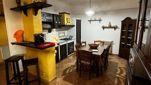 A compact kitchen with a dining area, featuring a tiled floor, wooden furniture, and a built-in oven.