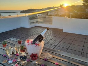 A terrace with a sunset view, a bottle of champagne, ice, strawberries, and blueberries.
