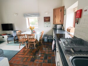 A compact kitchen with a dining table, chairs, a TV, and a microwave.