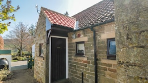 A stone building with a red-tiled roof, a black door, and a small window. - Glaisdale (Whitby)