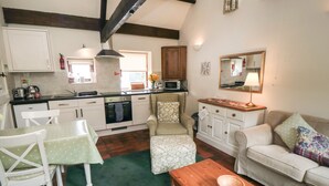 A compact living space with a kitchenette, a dining area, and a seating area with a sofa and a bench. - Glaisdale (Whitby)