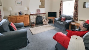 A cozy living room with a fireplace, a television, and comfortable seating. - Silver Birches (Whitby)