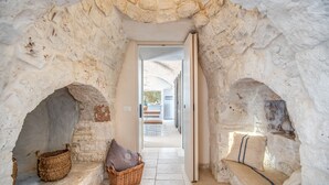 A stone-walled corridor with a bench and baskets. - Trulli, cicale e olive - Le Case di Valentina (Ceglie Messapica)