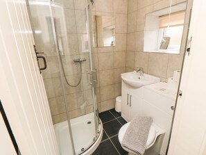 A bathroom with a glass-enclosed shower, a sink, and a toilet.