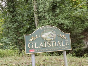 A welcome sign for Glaisdale, Northern Village of the Year 2002, with a stone bridge illustration.