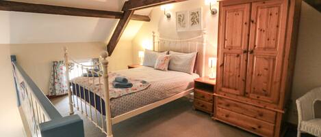 A bedroom with a bed, wooden wardrobe, and a chair.