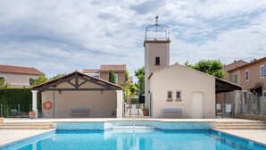 Uima-allas, jonka ympärillä on laatoitettu allasterassi, pelastusrengas ja pieni rakennus, jossa on torni.