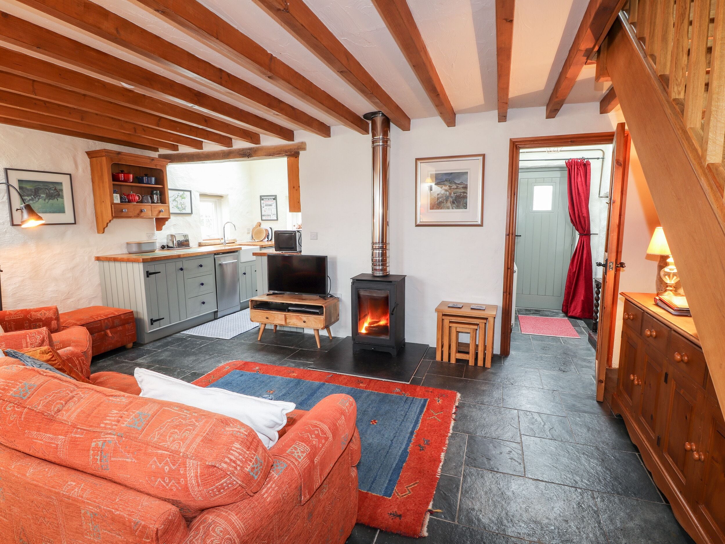 Una sala de estar acogedora con chimenea, un sofá, una televisión y una zona de cocina al fondo.