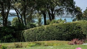 Un jardin aménagé avec une grande variété de plantes, une haie bien entretenue et une vue sur la mer.