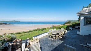 A patio with a table and chairs overlooking a beach. - Treverden (Wadebridge)
