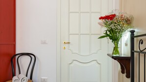 A room with a bed, a chair with towels, a white door, and a vase with flowers. - Don Pedro Rooms Vicerè di Toledo - Camera 3 (Napoli)