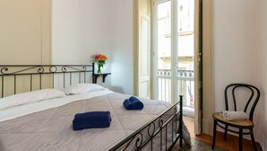 A neatly made bed with a striped bedspread, a pair of rolled towels, and a small bedside table with a vase of flowers. - Don Pedro Rooms Vicerè di Toledo - Camera 3 (Napoli)
