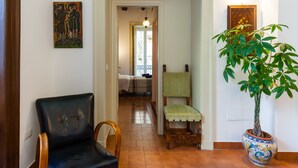 A hallway with a black leather chair, a wooden chair with a green cushion, and a potted plant. - Don Pedro Rooms Vicerè di Toledo - Camera 3 (Napoli)