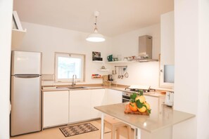 Modern kitchen with stainless steel appliances, oven, and sink, plus a small island and ample storage.